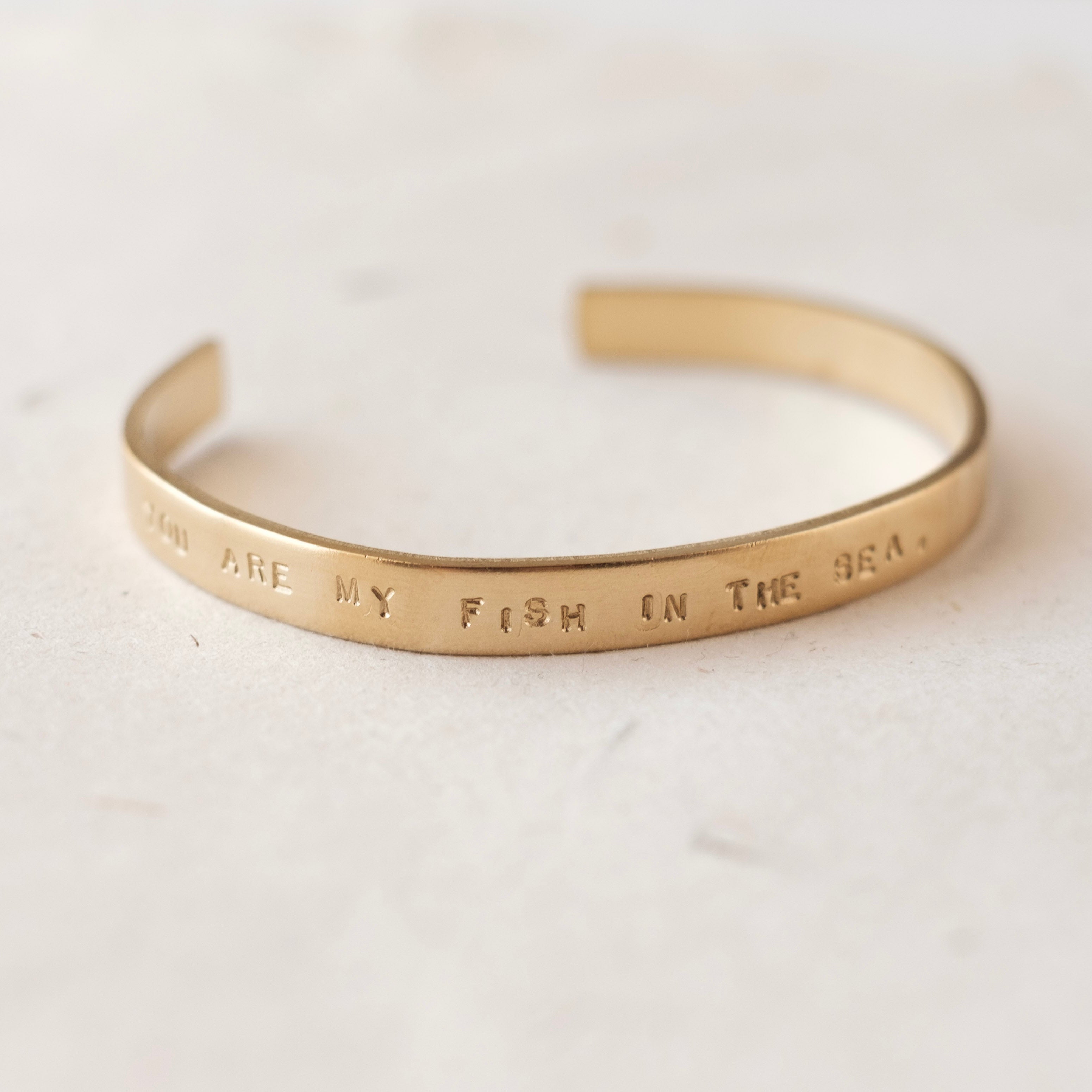 Gold bracelet with engraved text on a light background