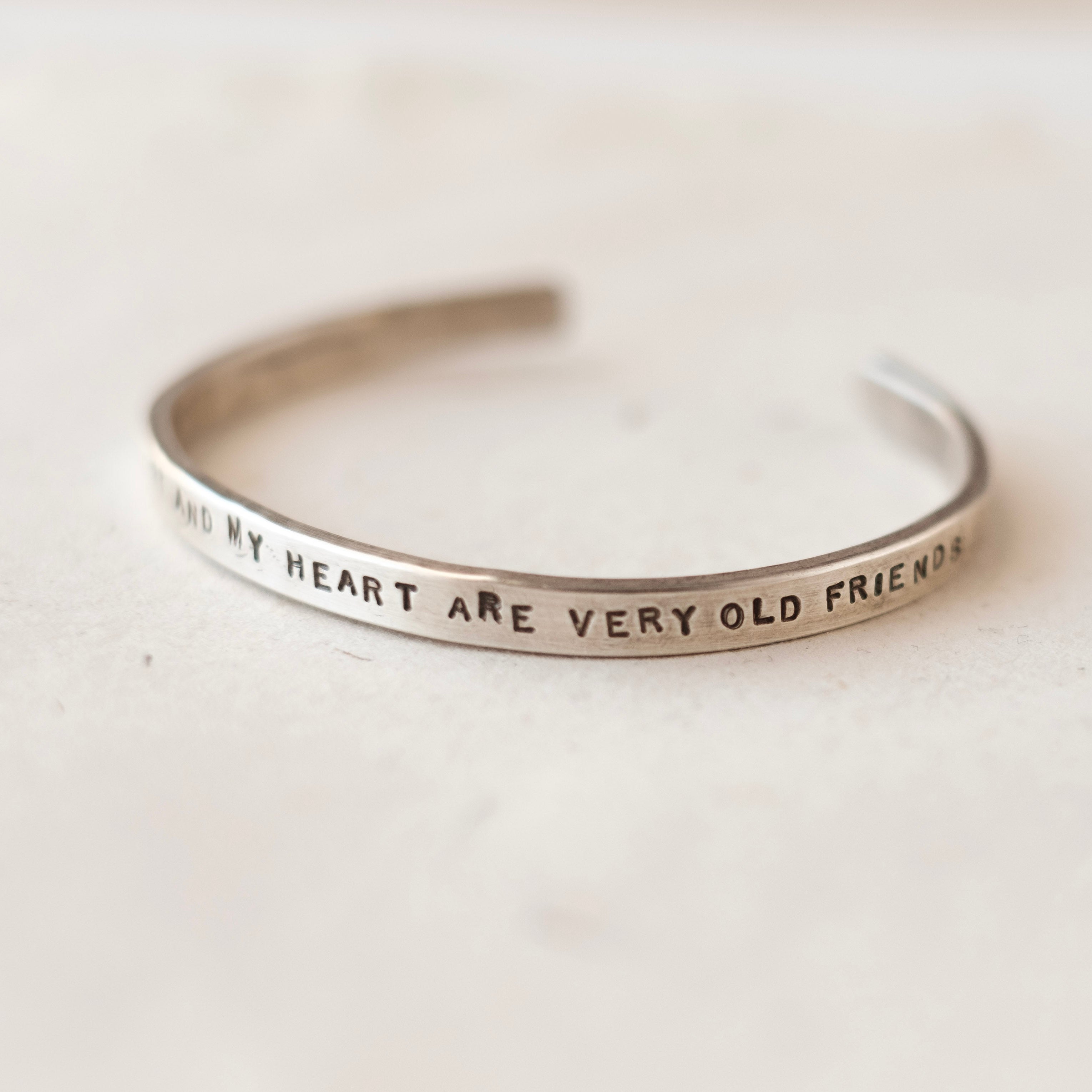Silver bracelet with engraved text on a light background