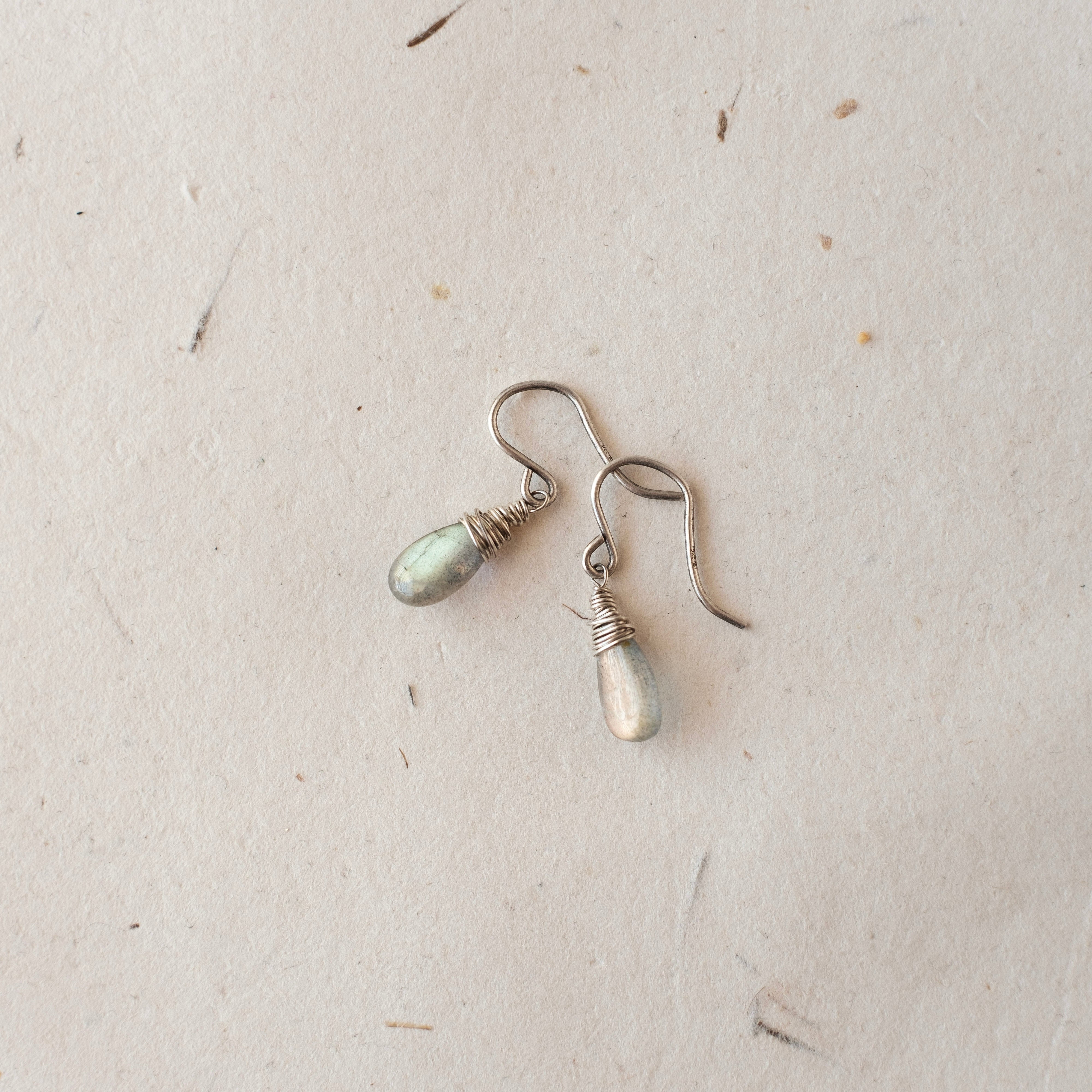 Pair of silver earrings on a textured beige surface