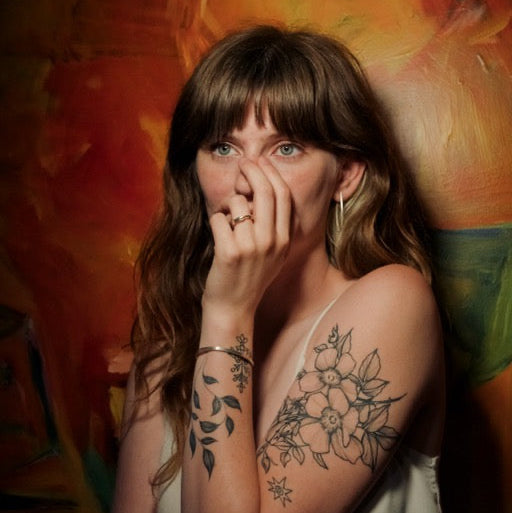 Woman with tattoos on her arms against a colorful abstract background