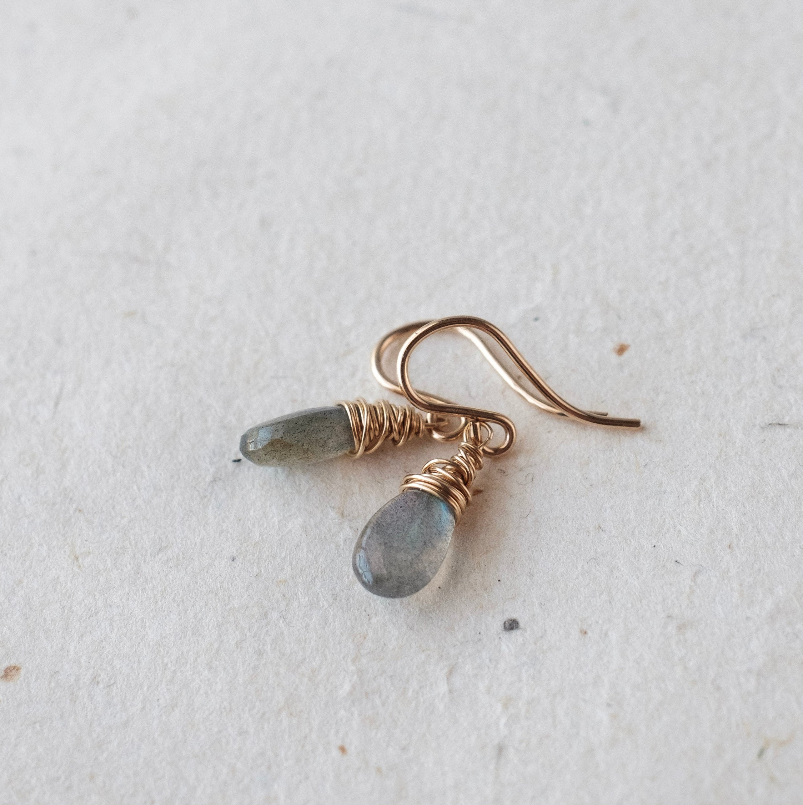 Pair of gold earrings with gray stones on a light gray background