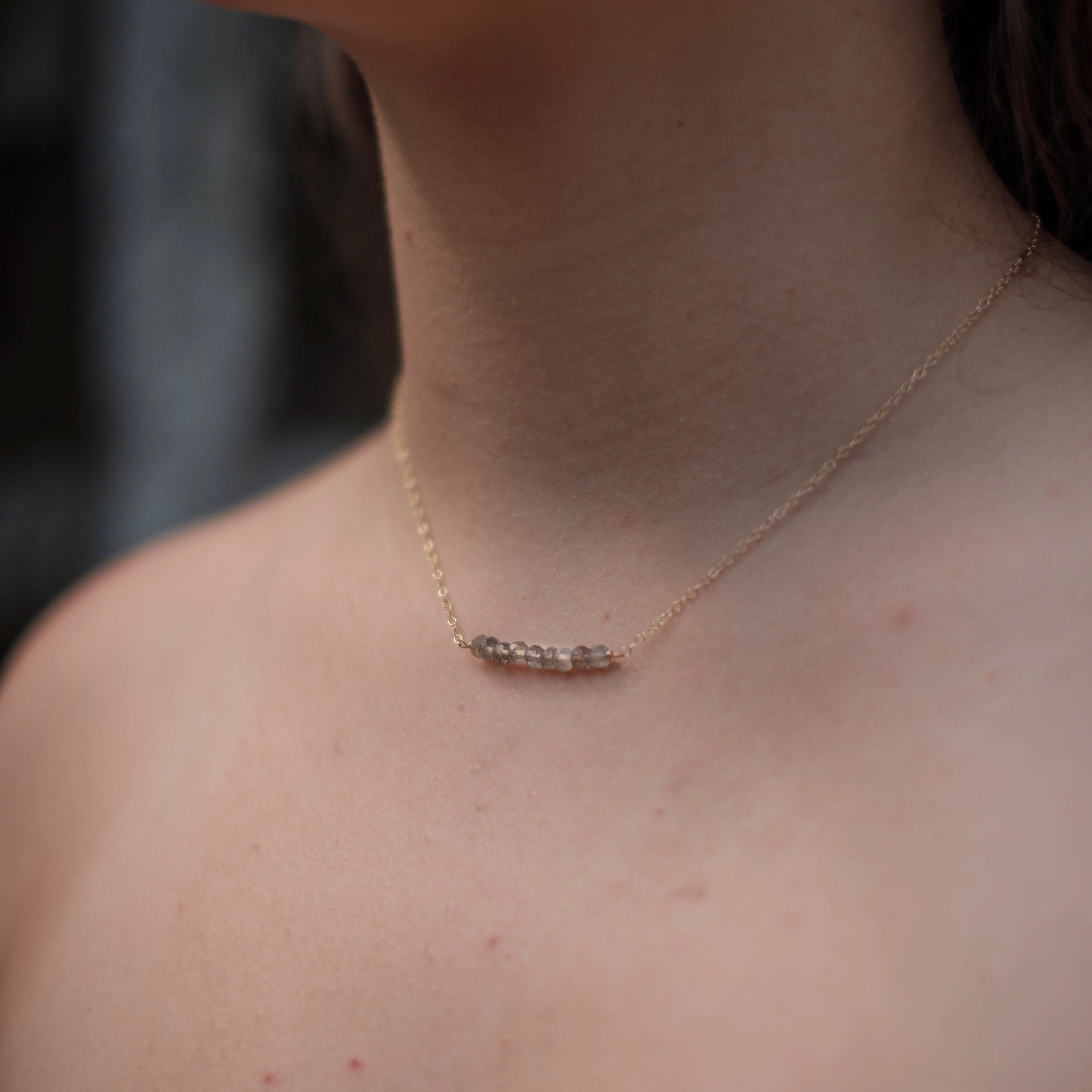 Close-up of a person wearing a delicate necklace with a blurred background