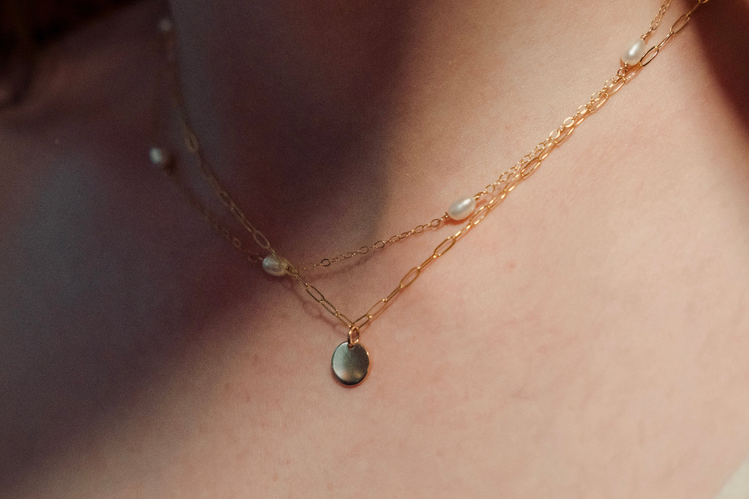 Gold necklace with small pendants on a person's neck