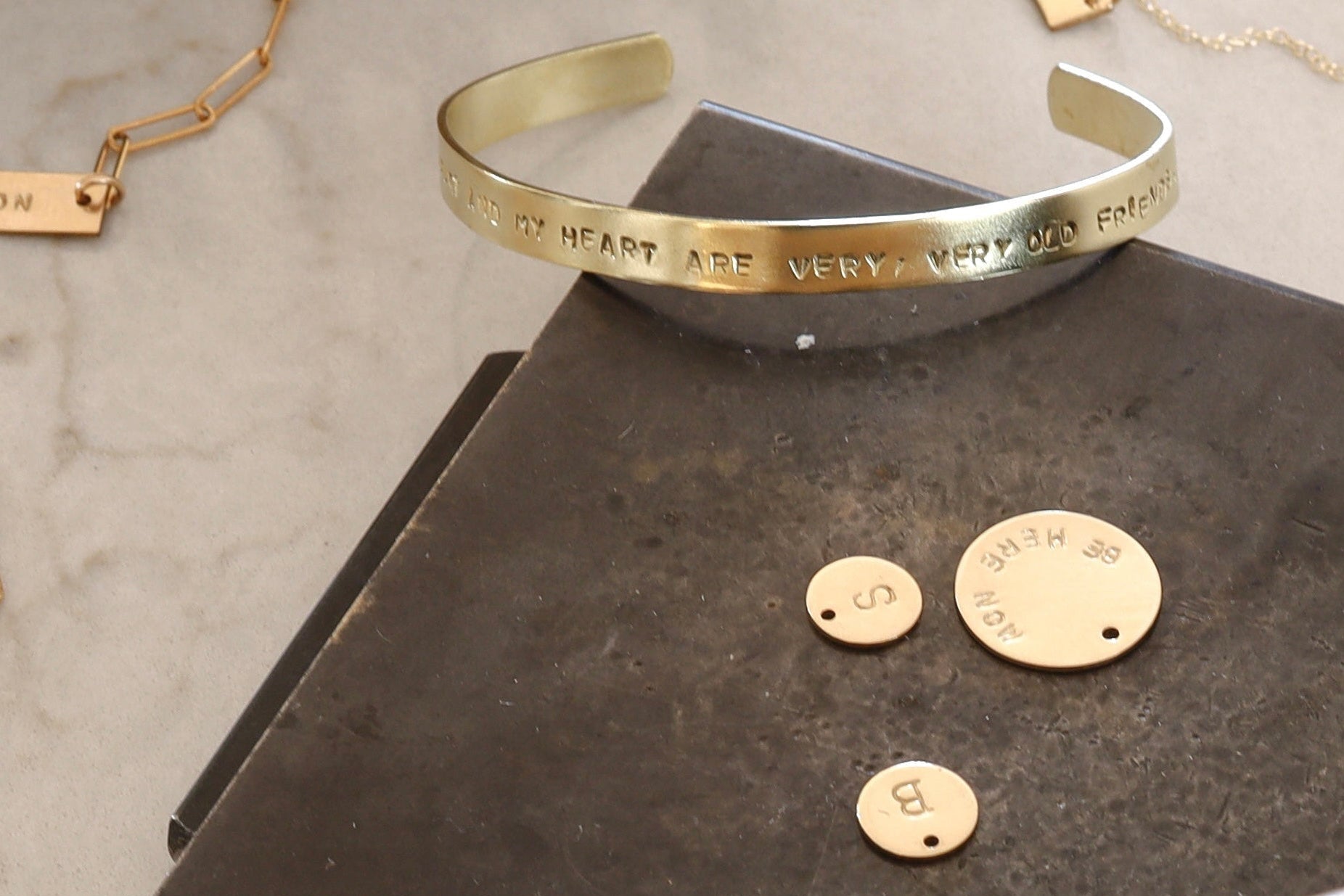 Gold bracelet with engraved text on a textured surface