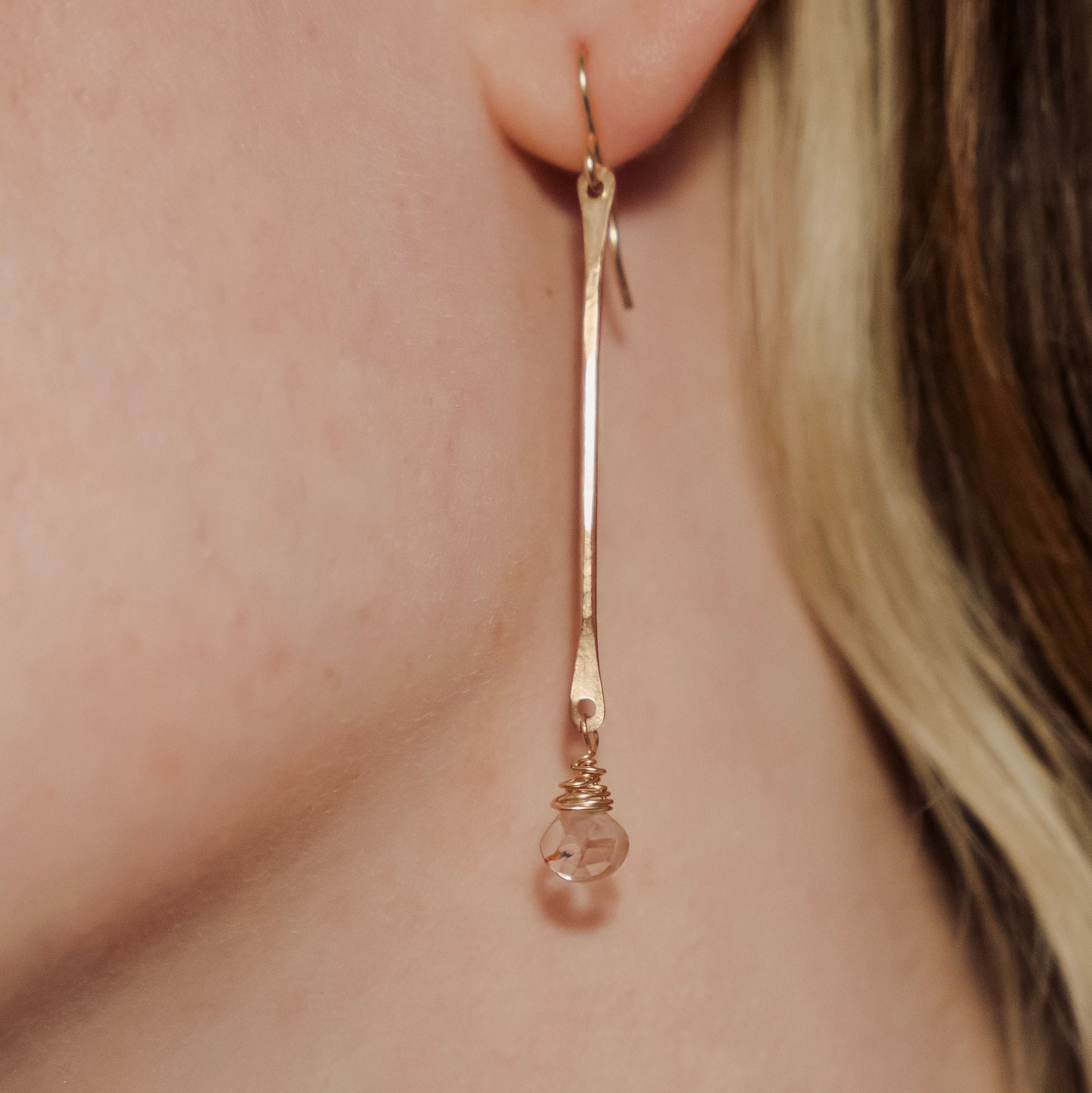 Gold earring worn by a person with a neutral background