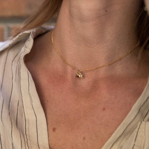 Close-up of a person wearing a gold necklace with a small pendant.