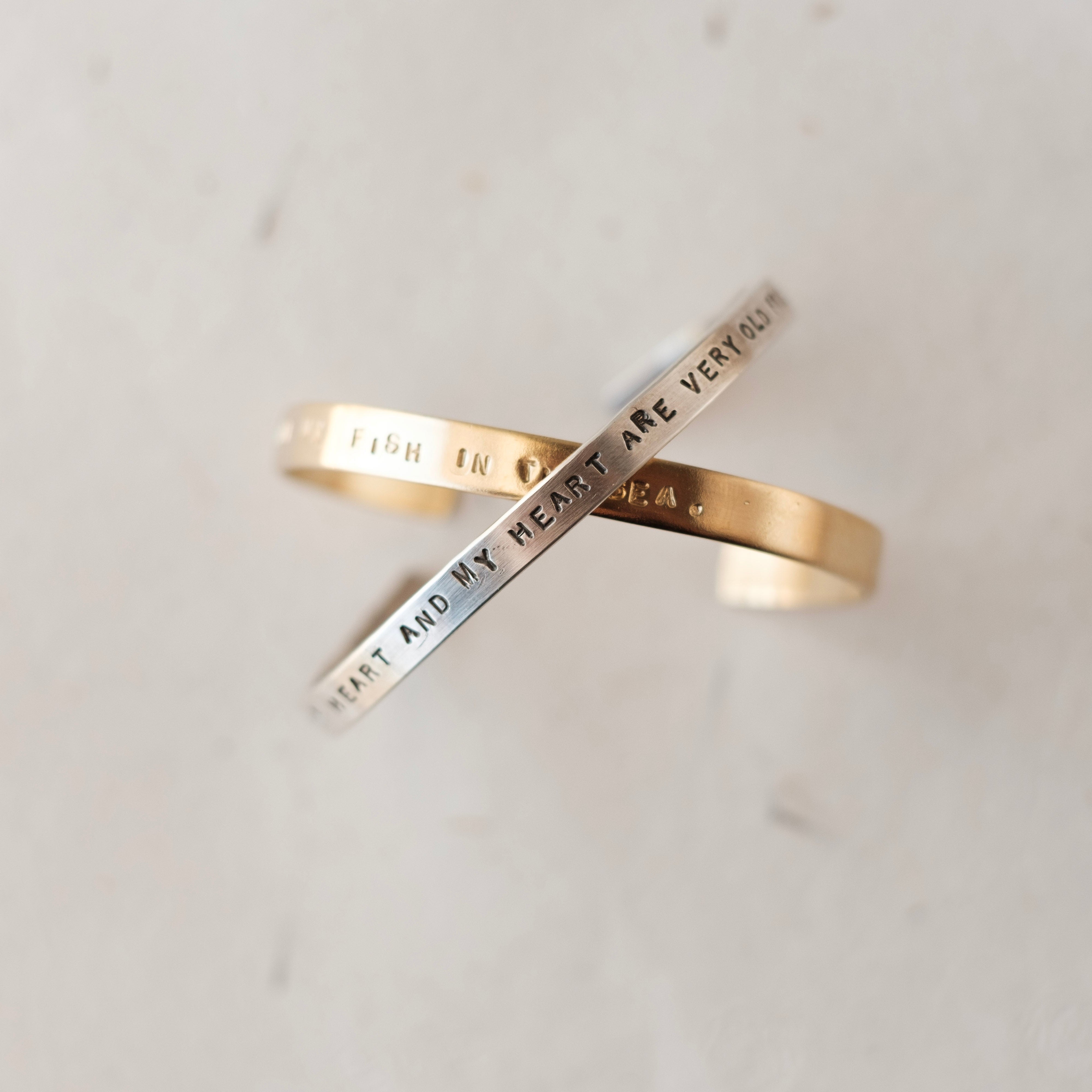 Two gold rings with engraved text on a light gray background