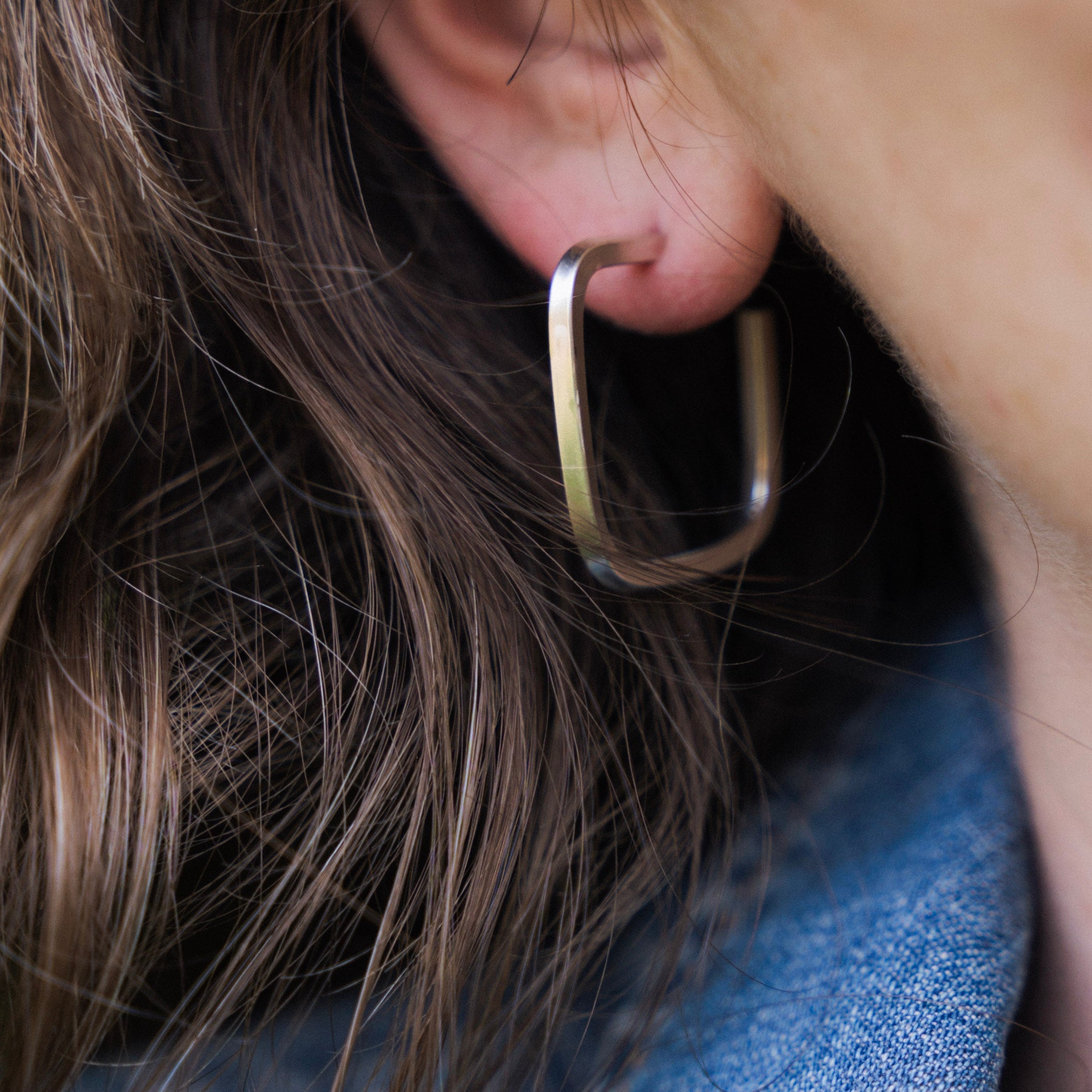 Close-up of a person wearing a hoop earring with a blurred background