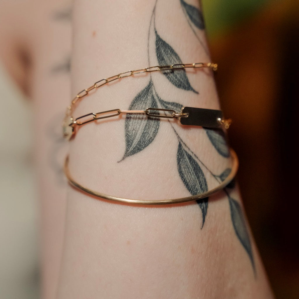 Gold bracelet on a wrist with tattoos