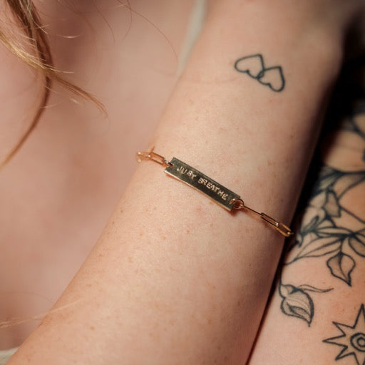 Gold bracelet on a wrist with tattoos