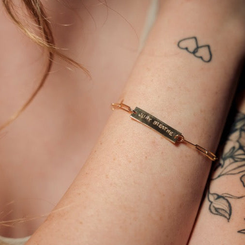 Gold bracelet on a wrist with tattoos