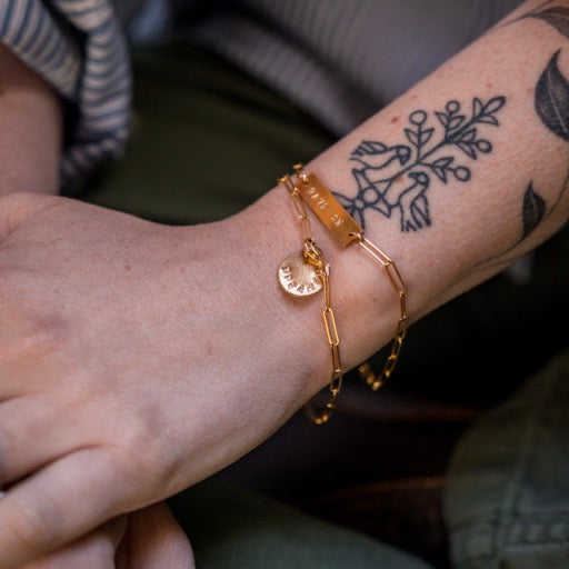 Gold bracelet on a wrist with tattoos