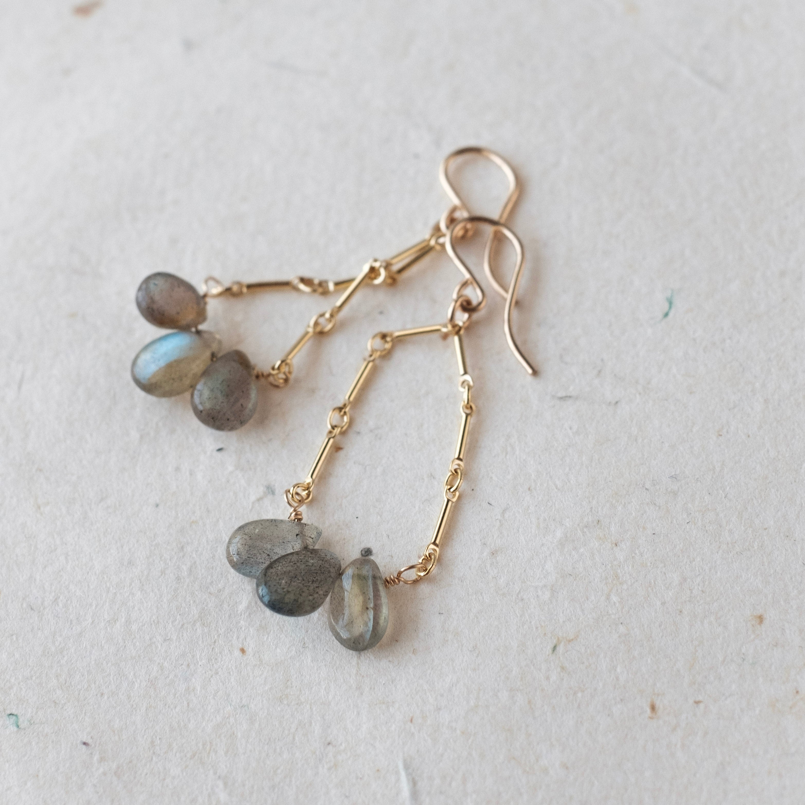 Gold earrings with Labradorite stones on a light gray background