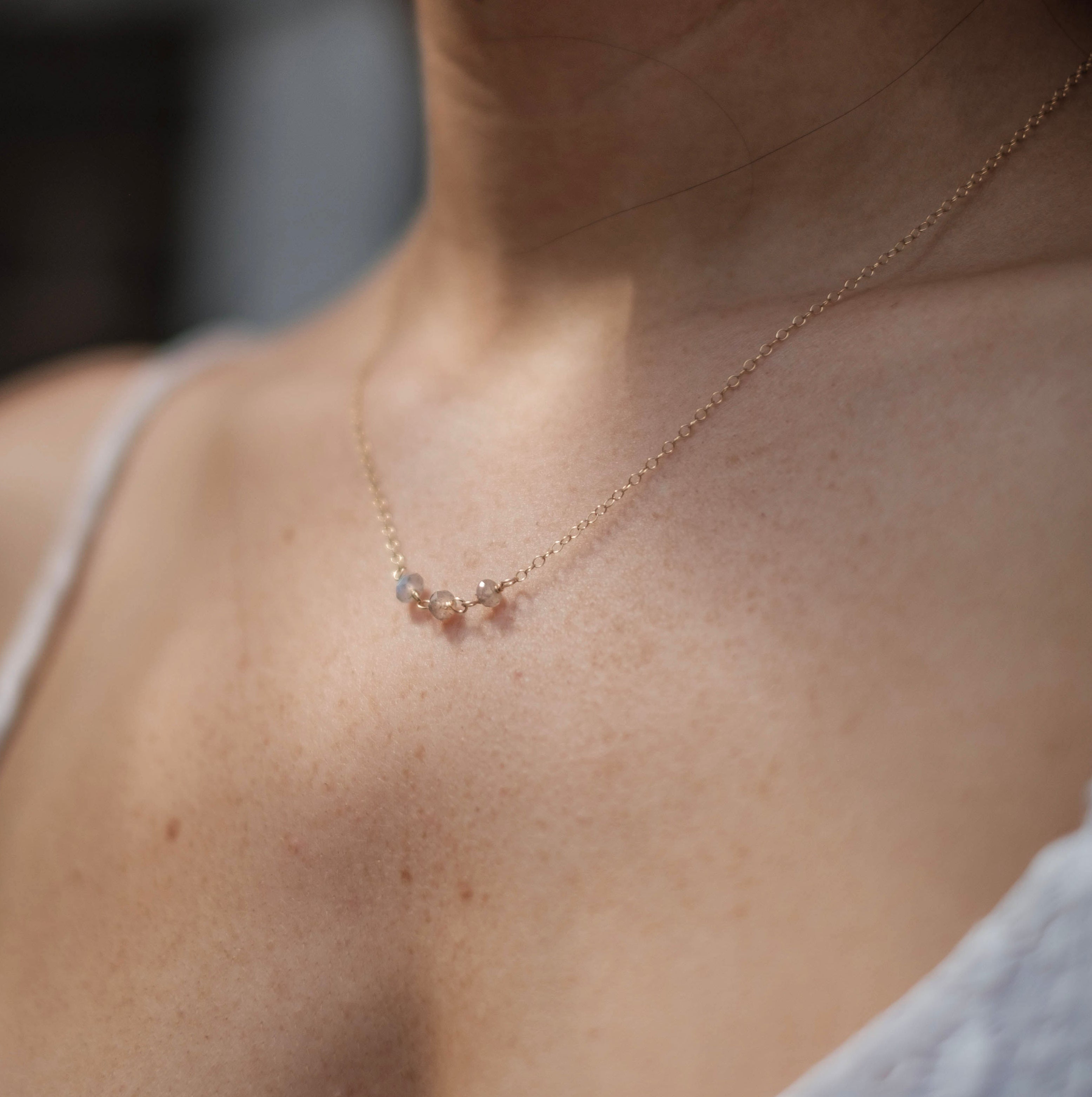 Close-up of a person wearing a delicate necklace with a blurred background