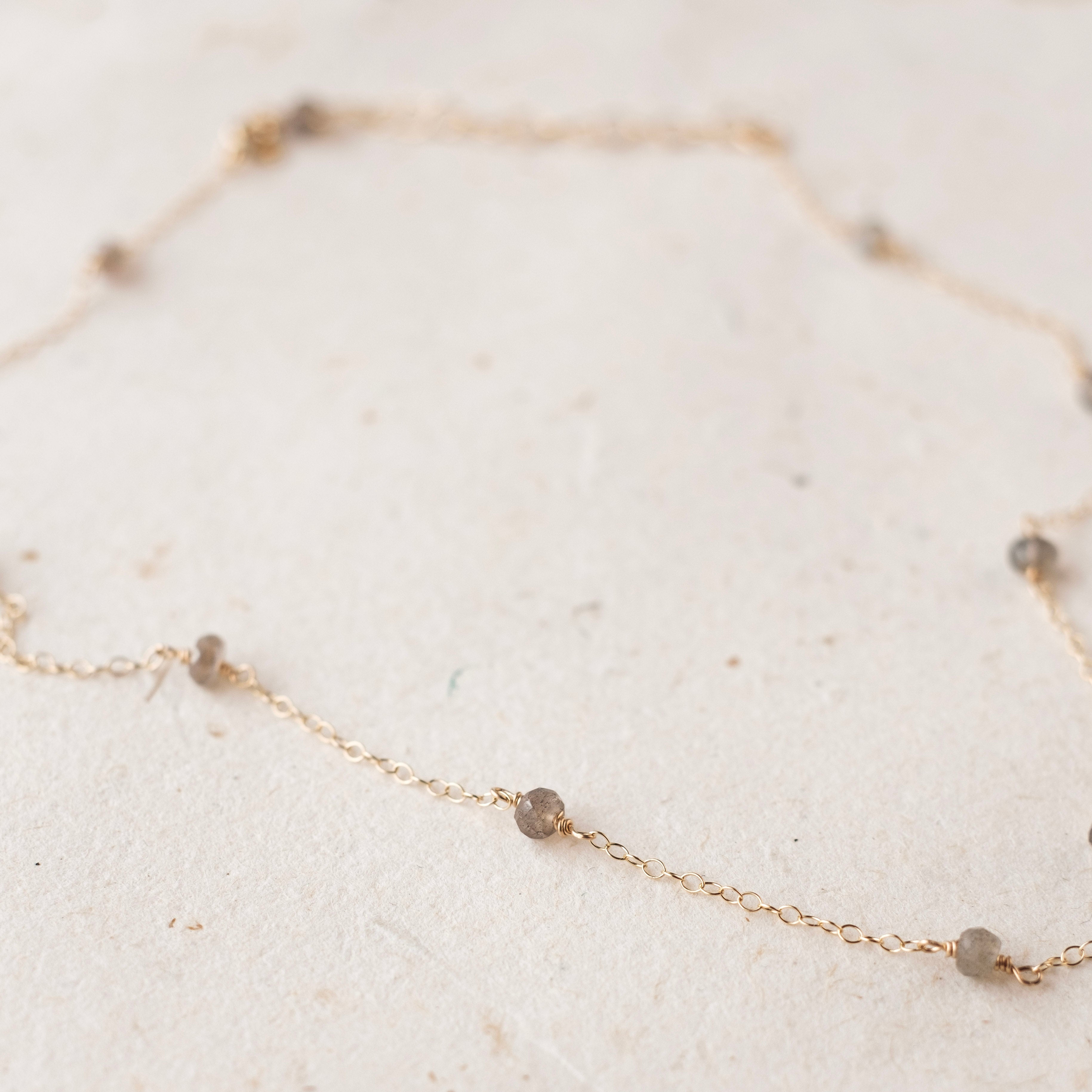 Delicate gold necklace with small beads on a light background