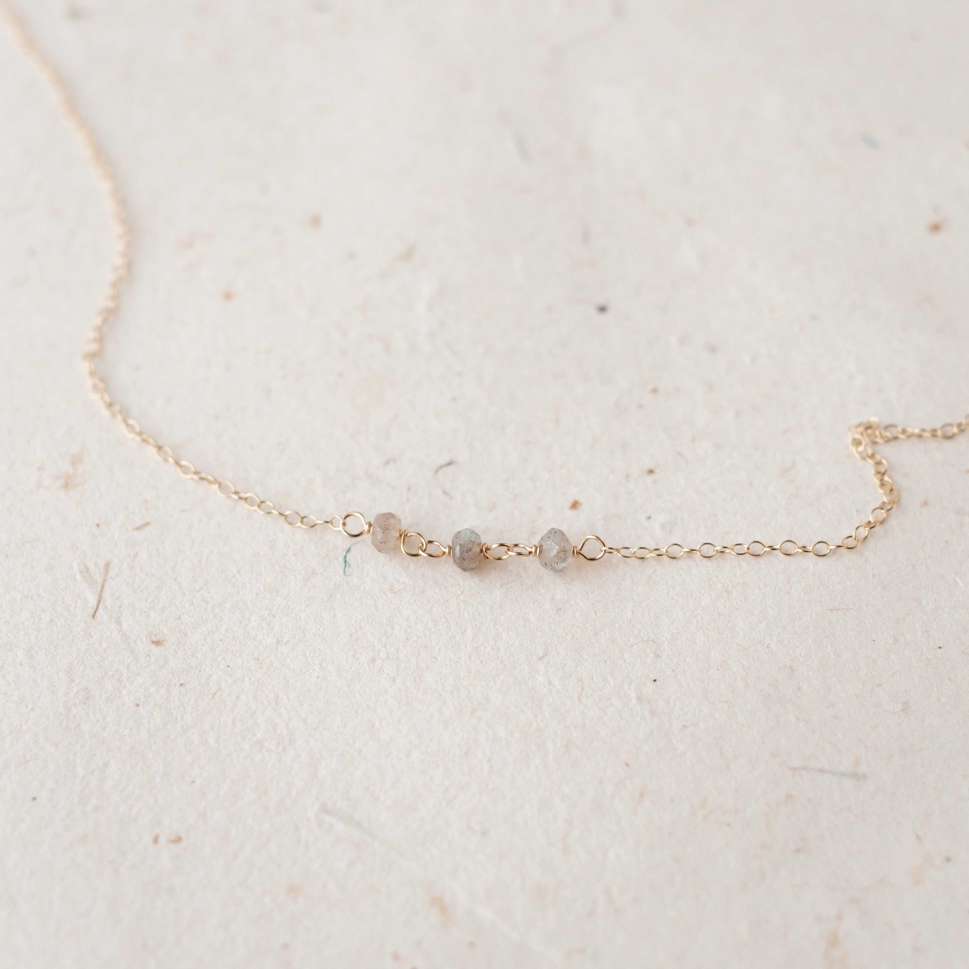 Delicate gold necklace with small beads on a light beige background