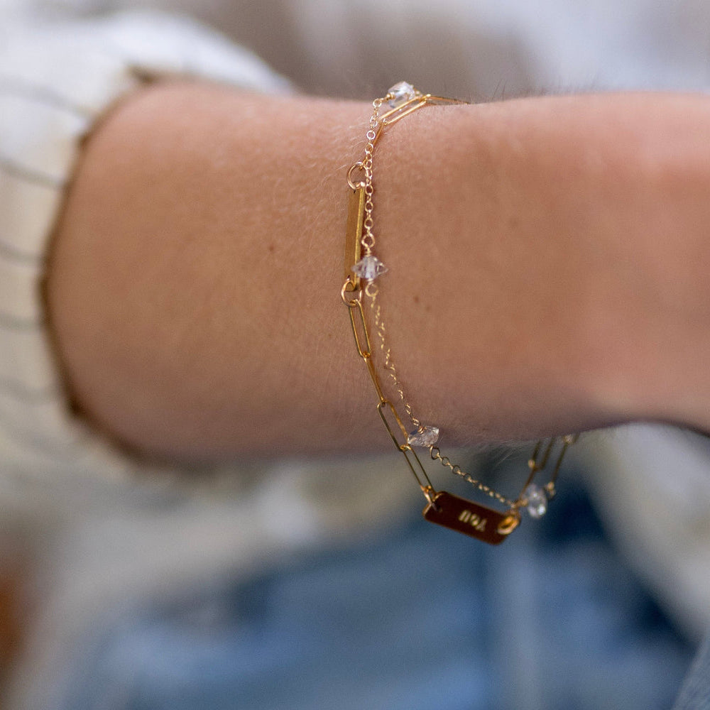 Close-up of a person's wrist wearing a gold bracelet with small beads.