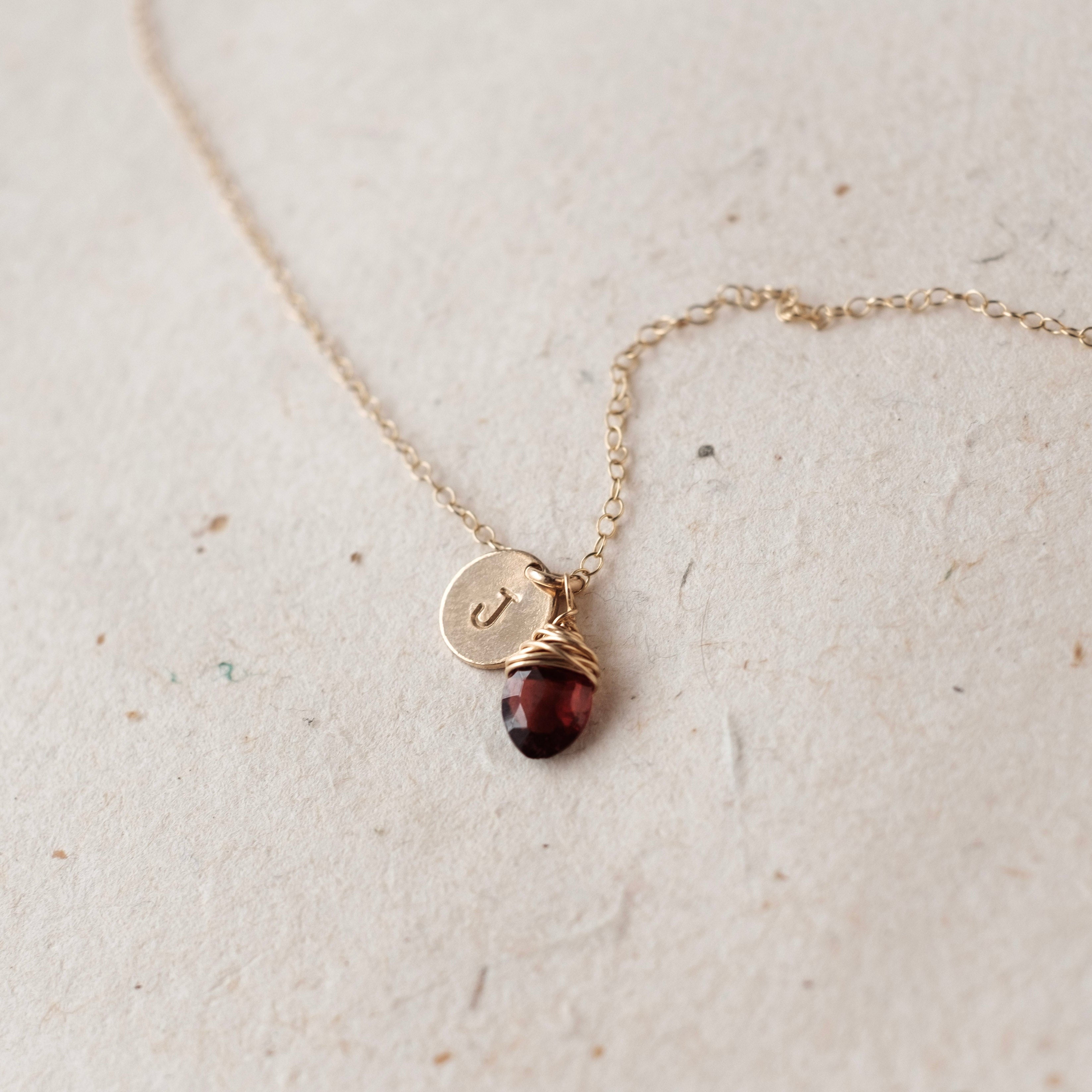 Gold necklace with a red gemstone pendant on a light background