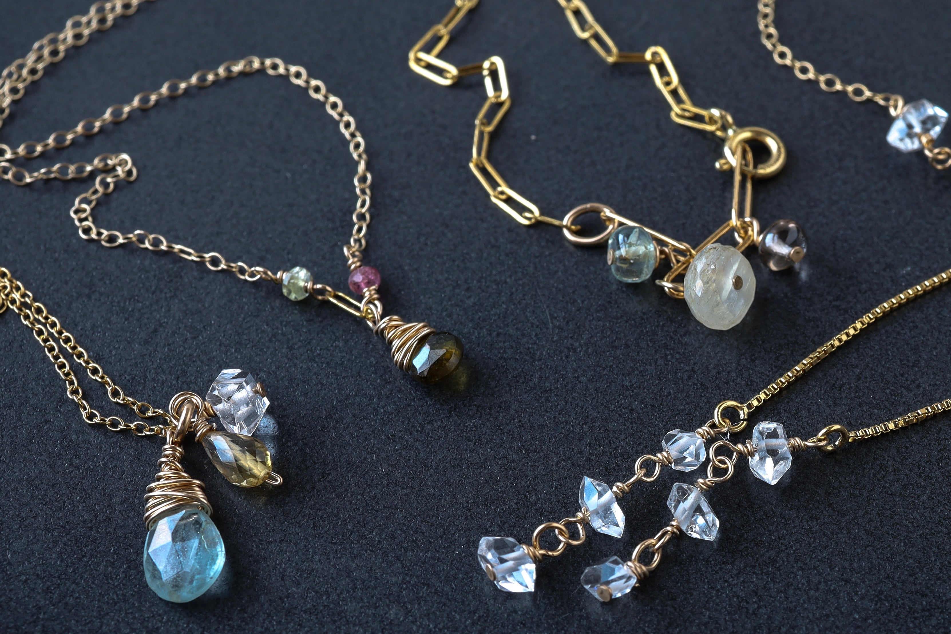 Gold necklaces with gemstone pendants on a dark background